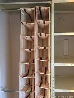 Full view of two vertical fabric shoe organizers with multiple compartments for storing shoes, showing striped beige fabric with dark and muted stripes.