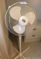 Front view of a white Hampton Bay floor fan showing blades and protective grill.