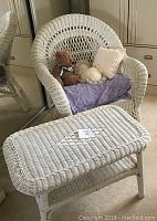 Overall view of white wicker chair with seat cushion and small table in front showing wicker weave details.