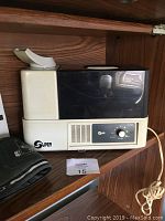 Super brand vaporizer humidifier with white base and black top inside a wood cabinet