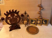 Overview of all items on table including sun and moon framed pictures, metal sun candle holder, metal wall candle holder, and ceramic bell hanger