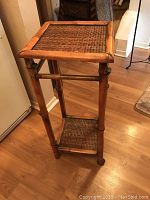 Full view of the rattan table showing woven top and bottom shelf, and four rattan legs.
