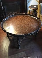 Full view of the round coffee table showing the wooden textured top with rattan wrapped rim and legs.