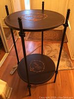 Full view of the round two-tier table showing the metal frame, decorative round surfaces, and leg details.