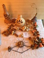 Three sets of clay indoor decorative wind chimes displayed together on white towel, showing bottle-shaped painted claying piece, various stringed bells, and ceramic sun face ornament with metal rays