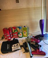 Photo showing the Swiffer mop, Monster handheld vacuum and accessories, cleaning liquids on fabric surface