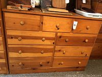 Front view of the oak dresser showing all 9 drawers with wooden knobs and natural wood finish.