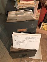 Photo of two metal sliding drawers filled with recipe cards labeled by category and a few cookbooks partially visible next to the drawers.