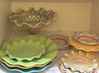 Bottom shelf featuring pastel scalloped dinner plates, small scalloped plates and pedestal cake display bowl