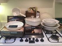 Photo of all Corning Ware French White items arranged on a stove, with boxes showing product names and some packaging.