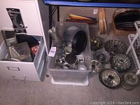 Wide shot showing multiple baking pans in a plastic bin and on the floor including fish mold, mini molds, and round pans.