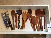 Full view of entire assortment of wooden serving utensils and one metal and wood knife.