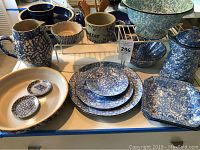 Photo showing full set of blue and white hand-painted Stangl pottery including pie dish, pitcher, butter crock, bowl, covered canister, plates and small figurine.