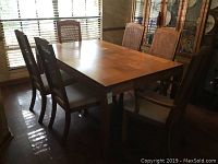 Wide shot showing entire dining table with 4 cane back chairs and 2 captain chairs around it, natural light from window.
