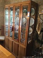 Front and side view of Thomasville china hutch with glass shelves displaying plates and glasses.