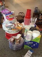 Image displaying assortment of disposable kitchen items on a kitchen counter including foam plates and bowls, red and clear plastic cups, paper coffee cups, and plastic trays.