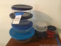 Photo showing 10 Pyrex glass bowls stacked in two columns with various colored plastic lids in blue, black, white, and red.