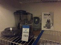 Ninja Master Prep food processor and accessories including blending container and chopping bowl, with instruction manual behind them