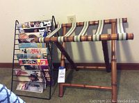 Black metal magazine rack filled with several magazines next to a bamboo suitcase stand with fabric straps