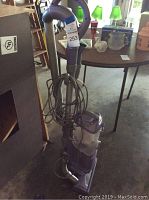 Photo showing front view of purple Shark Navigator vacuum cleaner with hose and power cord coiled around the handle.