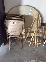 Full view of folded chairs, folded round table, and two wooden display easels