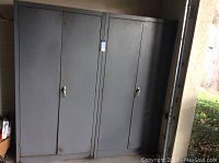 Two closed grey metal cabinets side by side with visible handles and minor rust at the base.