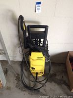 Front view of the yellow Karcher pressure washer with handle and coiled hose.