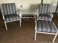 Patio set showing two metal framed chairs with striped cushions, glass-top rectangular end table, and ottoman with matching cushion