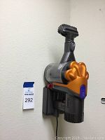 Dyson handheld vacuum mounted on wall with brush head attached