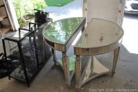 Pair of wooden demi lune tables with mirrored tops and shelves shown from a front angled view, illustrating shape and condition.