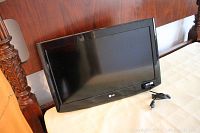 Front view of the 26 inch LG TV showing screen and power cord on beige furniture.