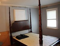 Assembled four-poster bed frame with mattress platform and boxspring leaning against wall