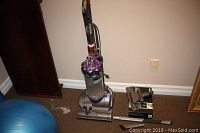 Dyson DC28 Animal upright vacuum cleaner next to accessories on brown carpet.