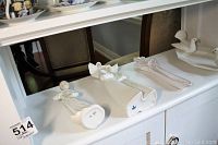 Photo showing the bottoms of two porcelain statues revealing Lladro and Nao markings, along with the ceramic celery holder and bird dish.