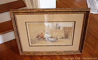 Framed watercolour and crayon painting showing a rustic scene with a stone wall and people, with clear front view.
