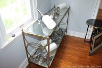 Side angle view showing metal frame, beveled glass top shelf, antiqued glass bottom shelf, and wheels.