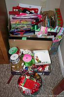 View of boxed ribbons, small seasonal decorations including bows and ornaments, and folded greeting cards.