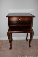 Front view of dark wood Bombay side table showing rectangular top and pull-out shelf with knob, standing on cabriole legs.