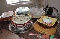 Wide view of assorted serving bowls, trays, and platters arranged on a kitchen island showcasing various materials and designs.