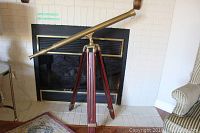 Full view of brass telescope and wooden tripod, angled right
