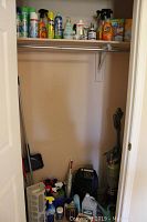 Photo showing another angle of the closet with vacuum on right side, space heater in middle, and various cleaning supplies lined up on the floor.