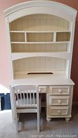 Front view of white wooden desk with four drawers and matching hutch shelving