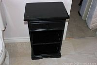 Front view of the black painted side table showing single drawer and two shelves