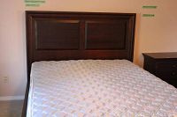 Front view of dark wooden headboard with two rectangular recessed panels, attached to platform frame with mattress on top