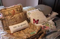 Queen size bedskirt, comforter, matching king size shams, assorted throw pillows with floral embroidery, printed pillows, and 'life is good' pillow arranged on bed.