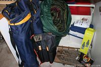 Photo showing camping chairs, coolers, sleeping bag, BBQ tools in bag, fire pit and fire starters