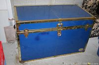 Front and side views of blue metal trunk with brass trim and lock, showing condition and features.