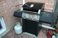 Front view of Centro 2800 propane barbecue grill with propane tank on side, showing three control knobs and hood with built-in thermometer.