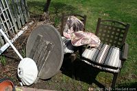 Two brown plastic patio chairs with cushions, round plastic table with woody finish top and detachable legs, white plastic umbrella base.