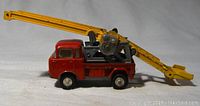 Side view of red Jeep FC 150 diecast truck with yellow crane extended horizontally.